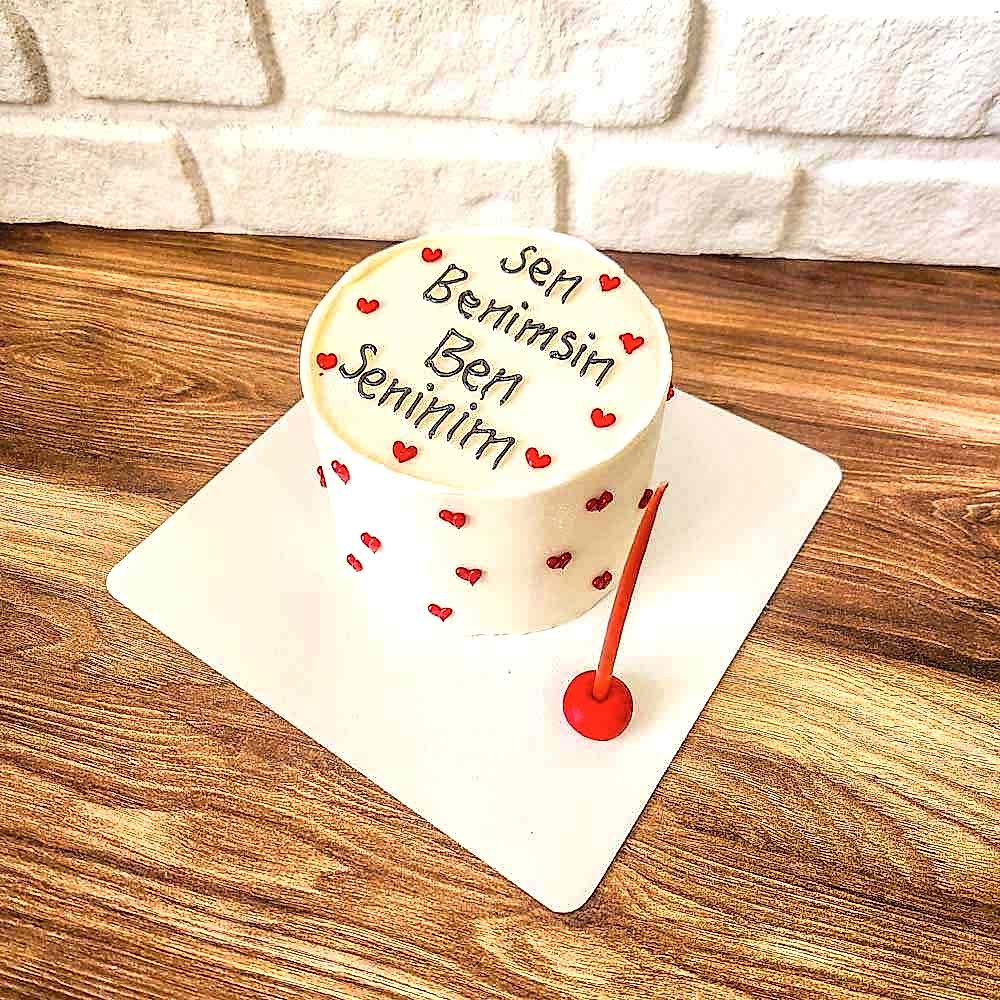 Kalp formunda tasarlanmış butik pasta, üzerinde “Sen Benimsin Ben Seninim” yazısı yer alır; romantik bağları simgeleyen sade ve duygusal bir tasarımla özel günlere anlam katar.