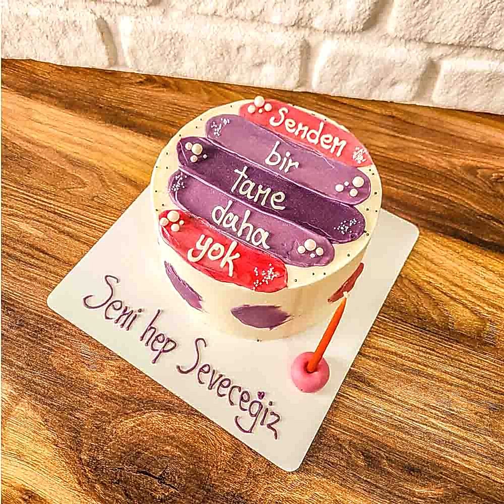 Beyaz zeminli butik pasta, üzerinde “Senden Bir Tane Daha Yok” yazısı ve pastel detaylarla süslenmiş; sevgi dolu ve özel hissettiren bir tasarım.