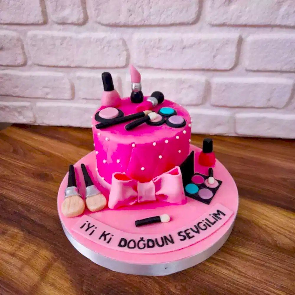 Ruj, fırça ve far paleti figürleriyle süslenmiş makyaj temalı butik pasta. Güzellik tutkunlarına özel renkli kutlama.