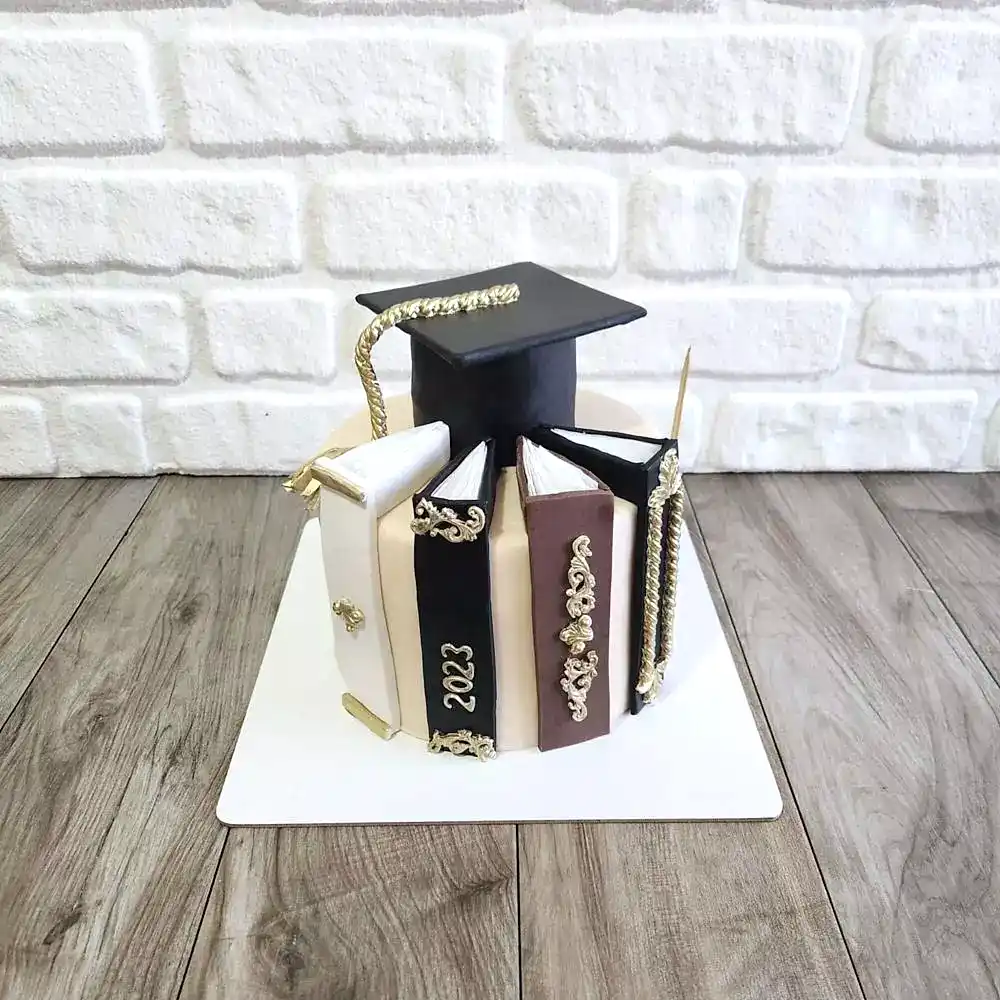 Kenarları kitap figürleriyle süslenmiş mezuniyet temalı butik pasta. Akademik başarıya özel zarif kutlama tasarımı.
