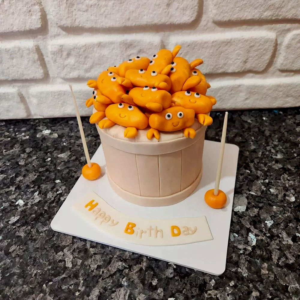 Kova içinde dolu dolu yengeç figürleriyle süslenmiş eğlenceli butik pasta. Sahil ruhuna tatlı bir gönderme!